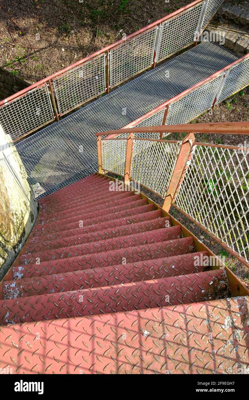 Vecchi gradini arrugginiti che conducono al piano inferiore ad un piccolo ponte Foto Stock