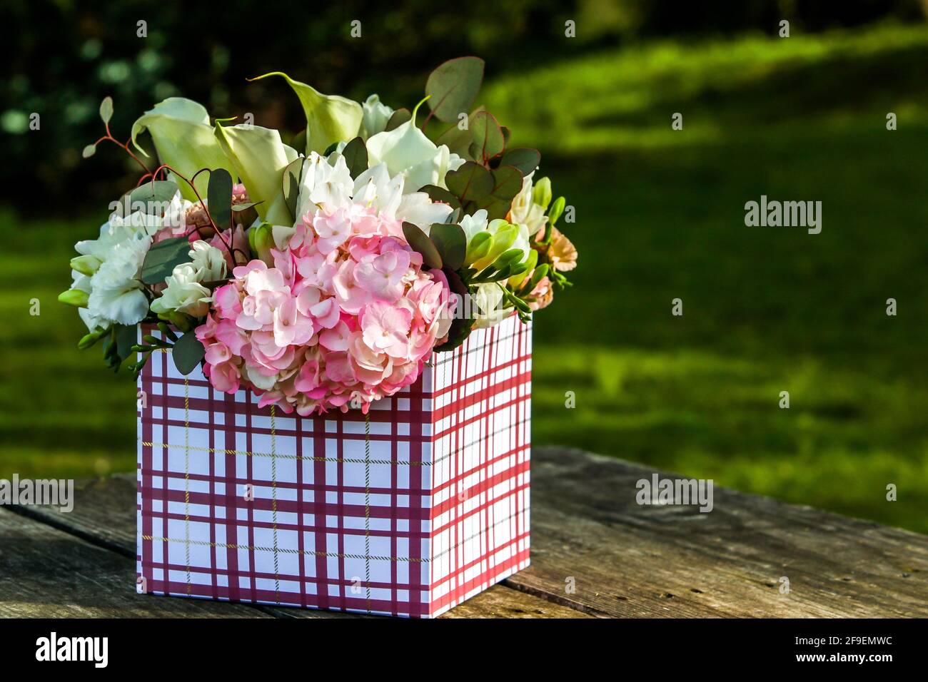 Fiori in confezione regalo all'esterno su tavolo di legno con testo spazio Foto Stock