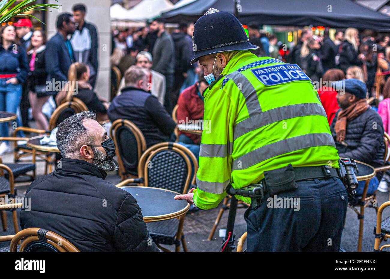 Un poliziotto mascherato parla con un civile, Soho, Londra, Inghilterra, Regno Unito. Foto Stock
