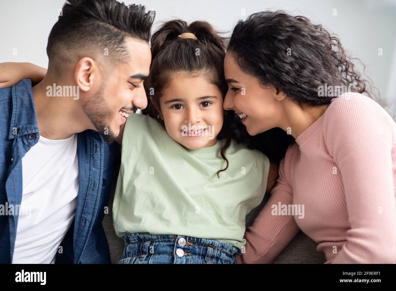 Amore parentale. Felici genitori arabi che coccolano la loro piccola figlia carina a casa Foto Stock