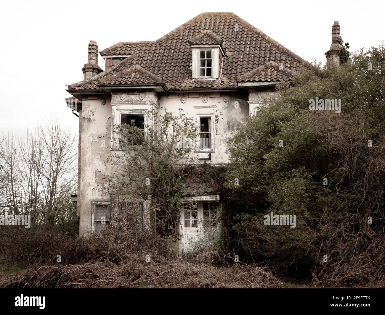 Una parte abbandonata rovinata casa perduta tra alberi e arbusti Foto Stock