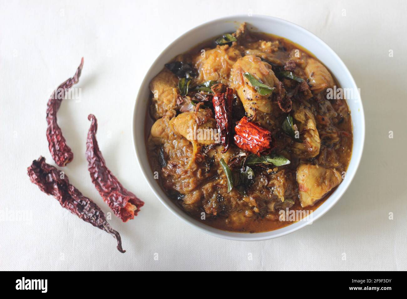 Curry di pollo in stile Kerala in olio di cocco con polvere di masala fatta in casa. Scatto su sfondo bianco. Foto Stock