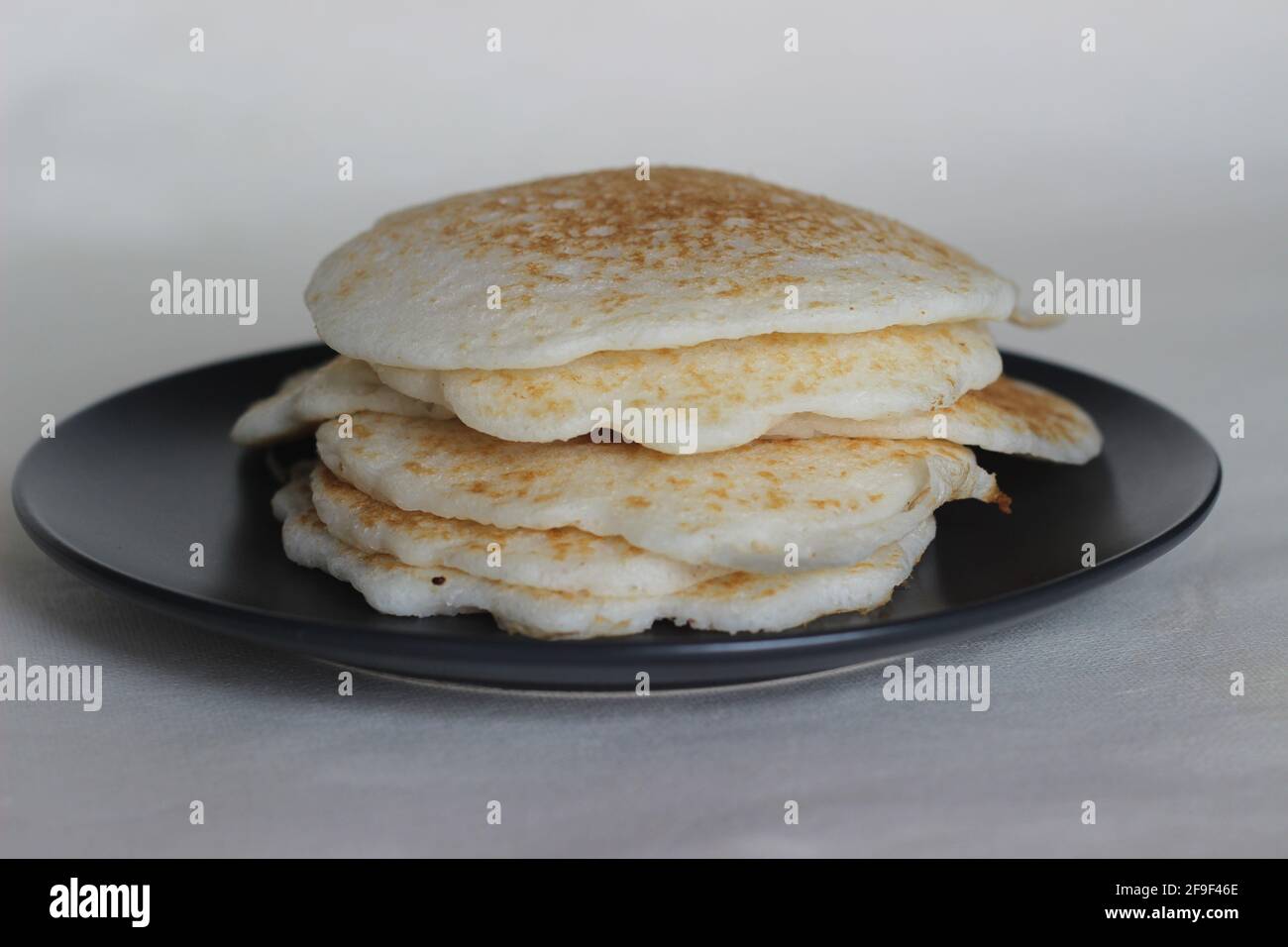 Frittelle di riso fatte in casa con pastella di riso fermentata e cocco grattugiato. Il piatto preferito per la colazione del Kerala chiamato Kallappam. Ripresa sulla parte posteriore bianca Foto Stock