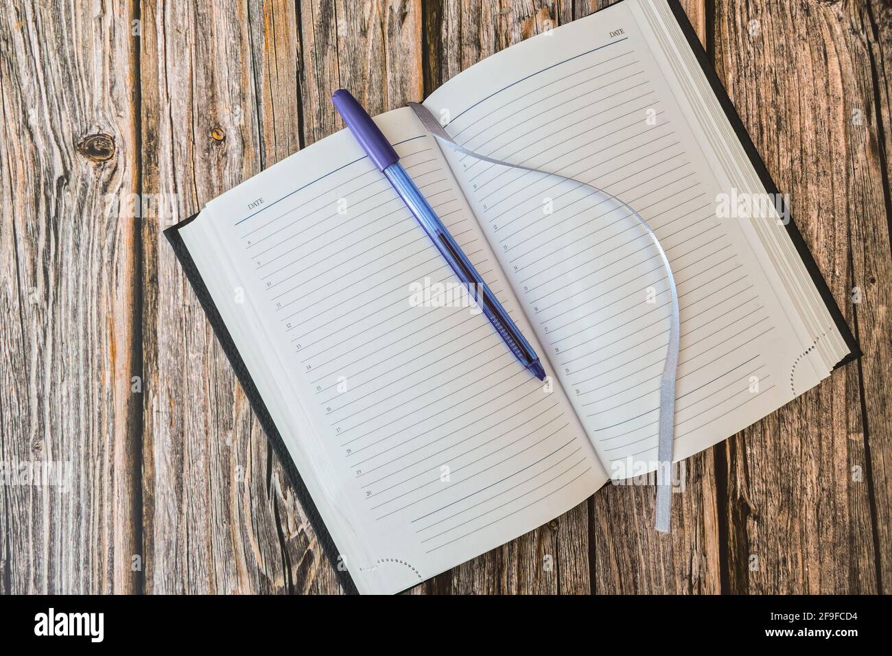 Aperto diario o quaderno per note con penna su legno vista dall'alto del tavolo Foto Stock