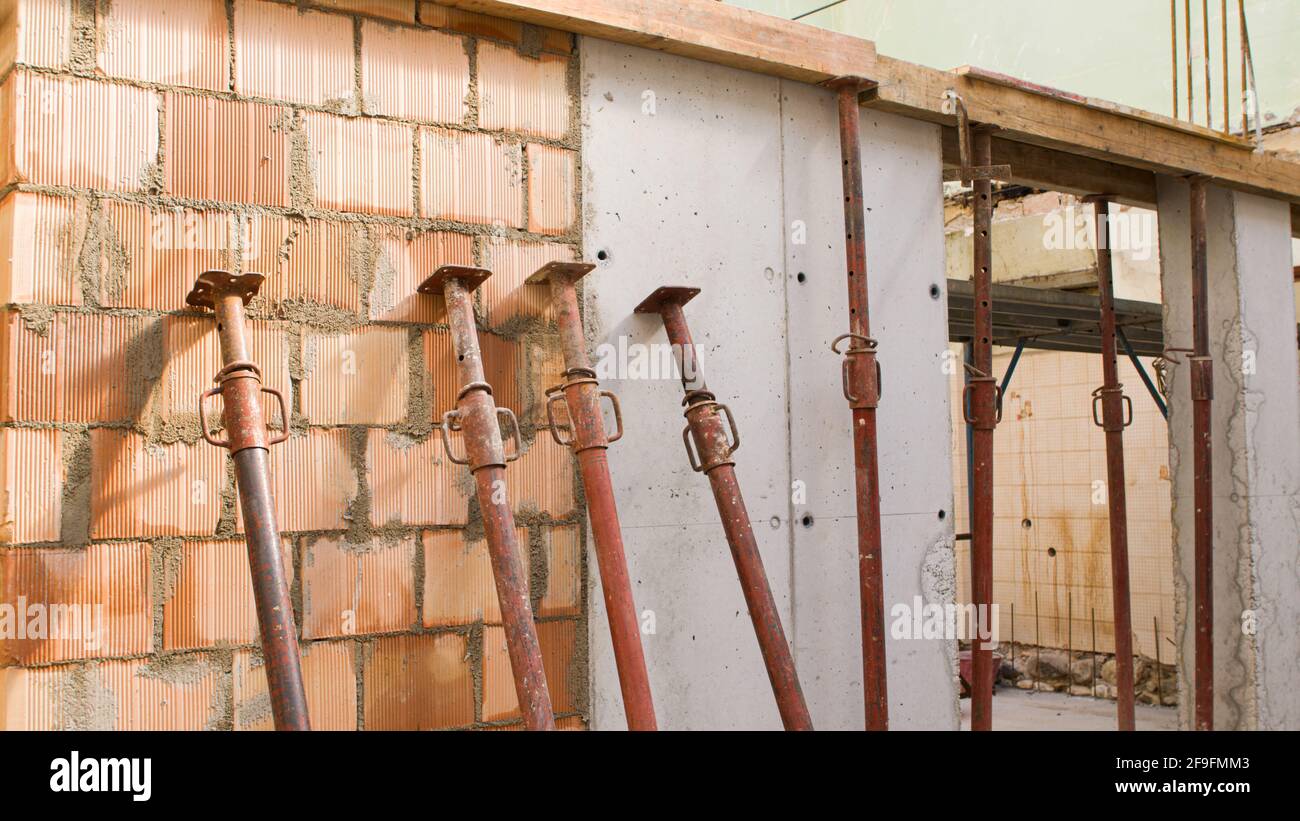 muro di mattoni di un luogo di costruzione con i puntelli di ferro e.  cemento armato Foto stock - Alamy
