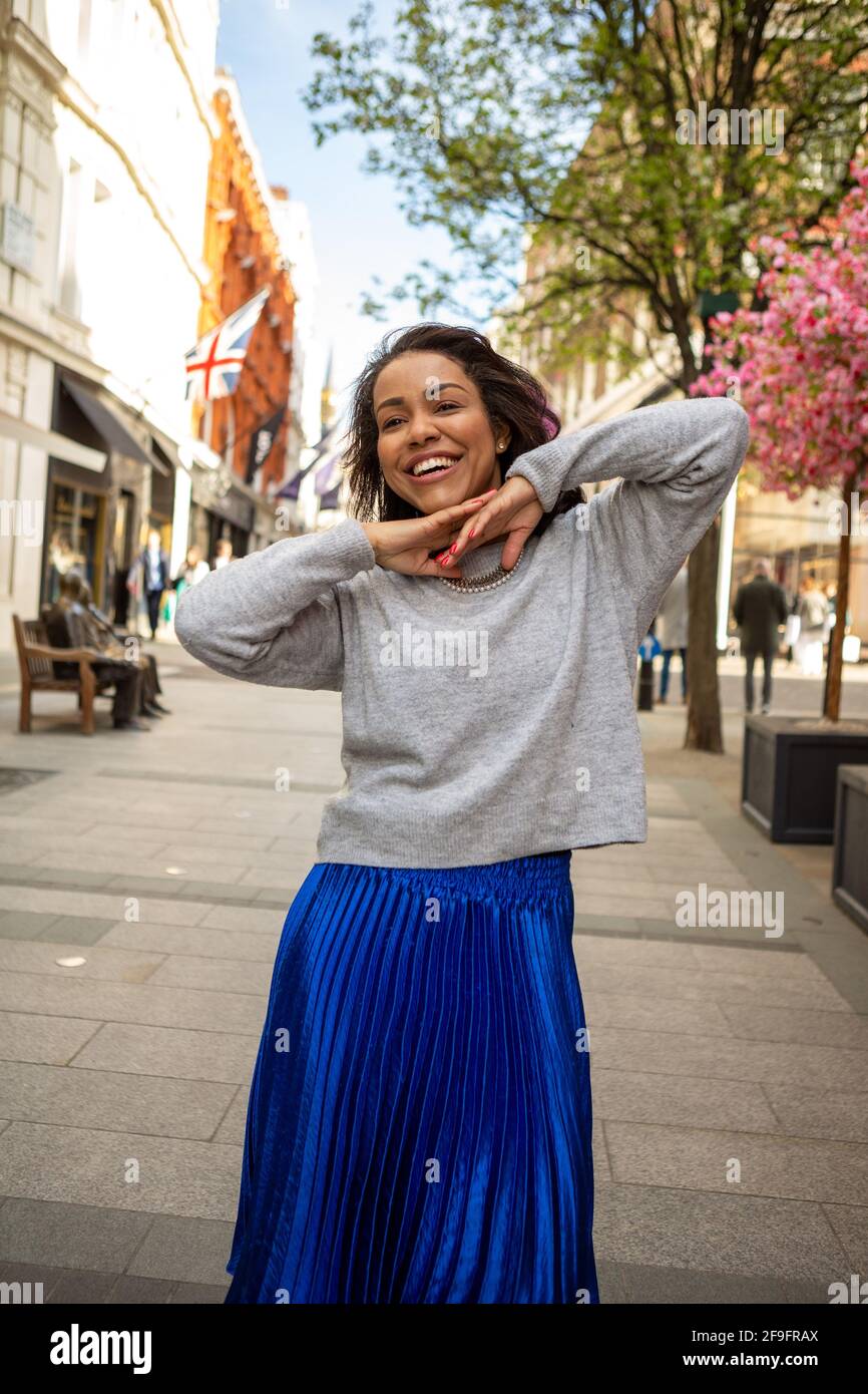 Un modello che indossa un ponticello grigio H M con una gonna lunga in Antropologie blu e scarpe Bershka in argento viste durante una foto in stile Street a Bond Street Londra Foto