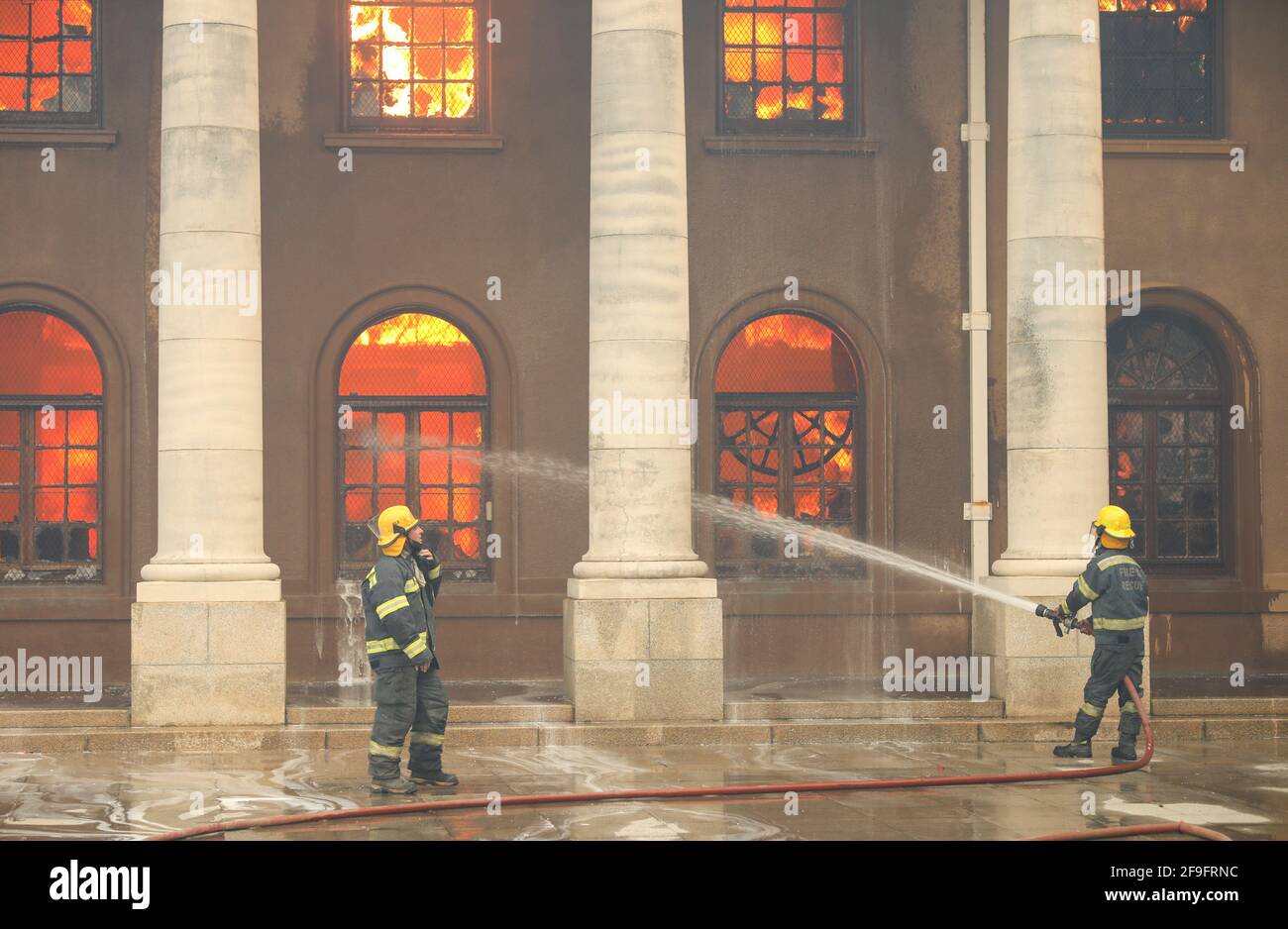 I vigili del fuoco combattono le fiamme mentre la biblioteca dell'Università di Città del Capo brucia dopo che un fuoco di funghi è scoppiato sulle pendici di Table Mountain a Città del Capo, Sudafrica, 18 aprile 2021. REUTERS/Mike Hutchings Foto Stock