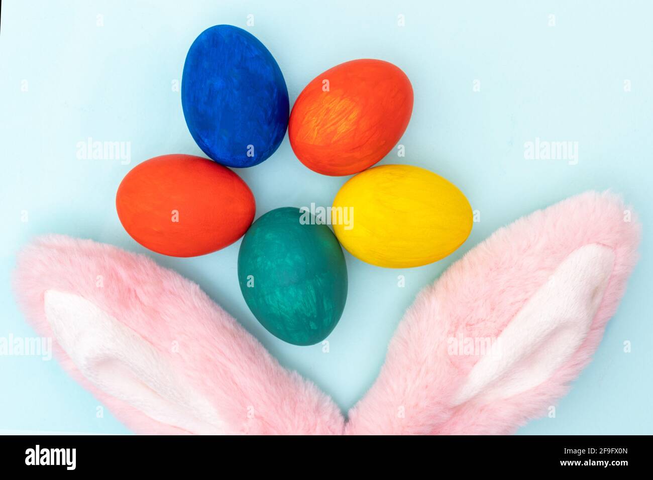 Buon concetto di Pasqua. Uova di Pasqua dipinte a mano e orecchie di coniglio rosa su sfondo bianco. Carta Pasqua minimalista. Foto Stock