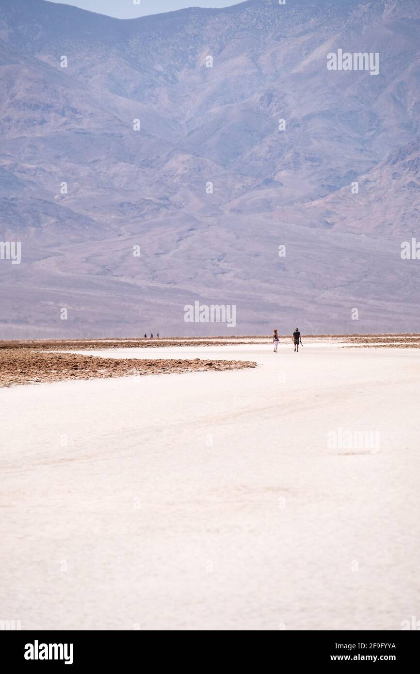 Personaggi umani molto lontani sulle distese di sale bianco a. Bacino di Badwater presso il Parco Nazionale della Death Valley Foto Stock