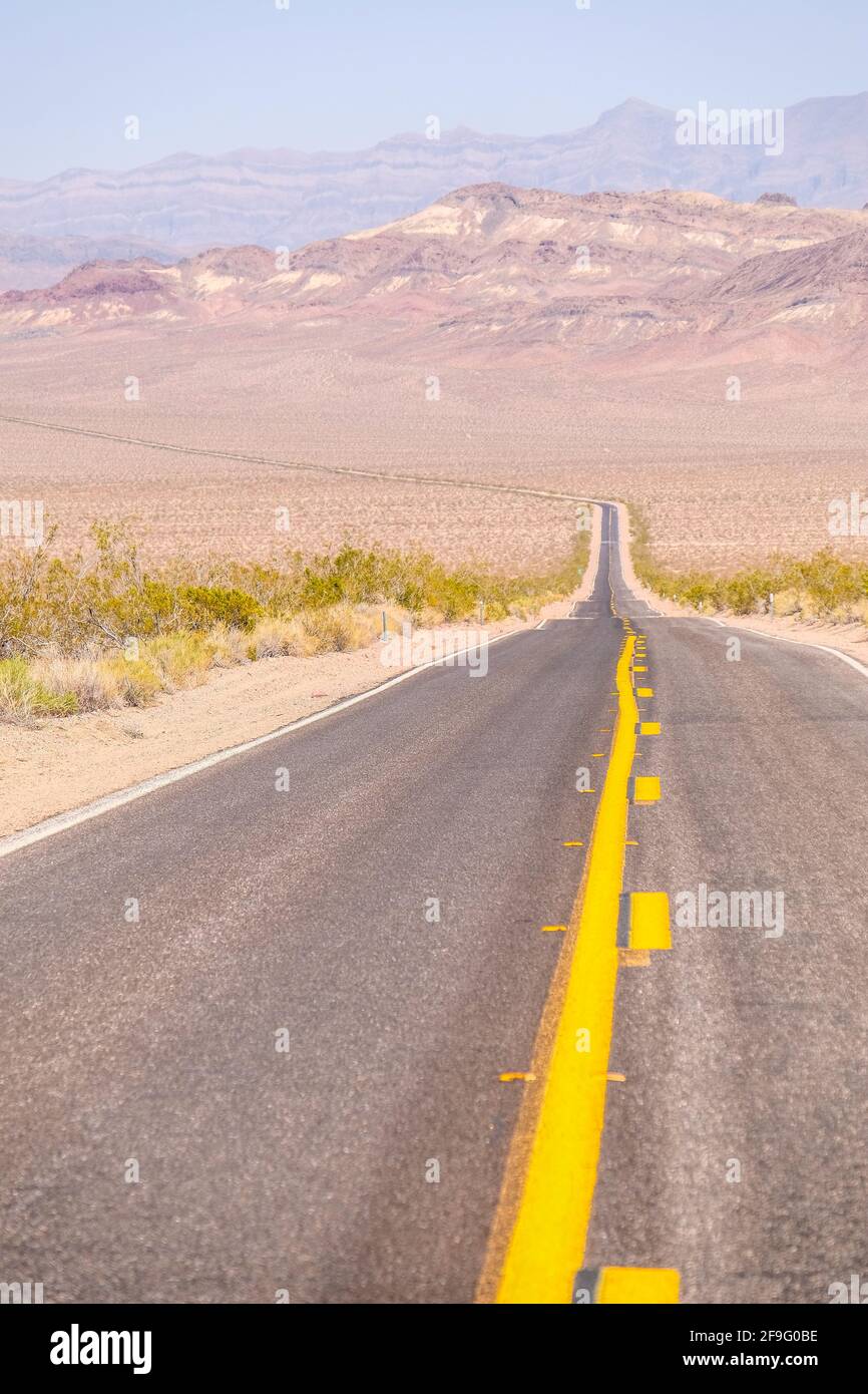 La linea gialla di traffico medio sulla Blacktop Empty Highway si estende in Far Horizon al Death Valley National Park Foto Stock