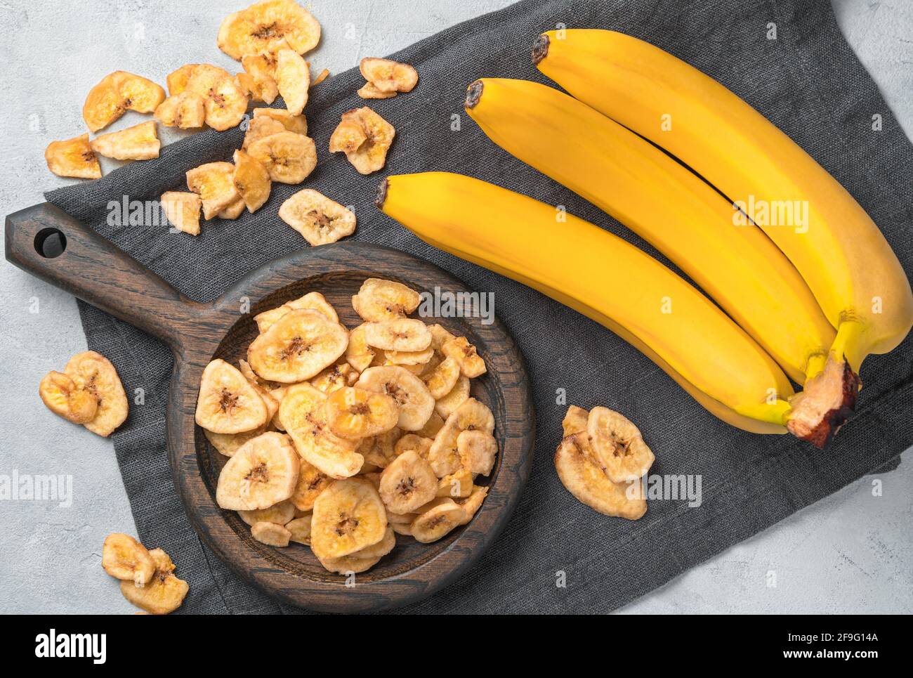 Banana chips e banane fresche su sfondo grigio. Vista dall'alto. Dolci sani naturali. Foto Stock