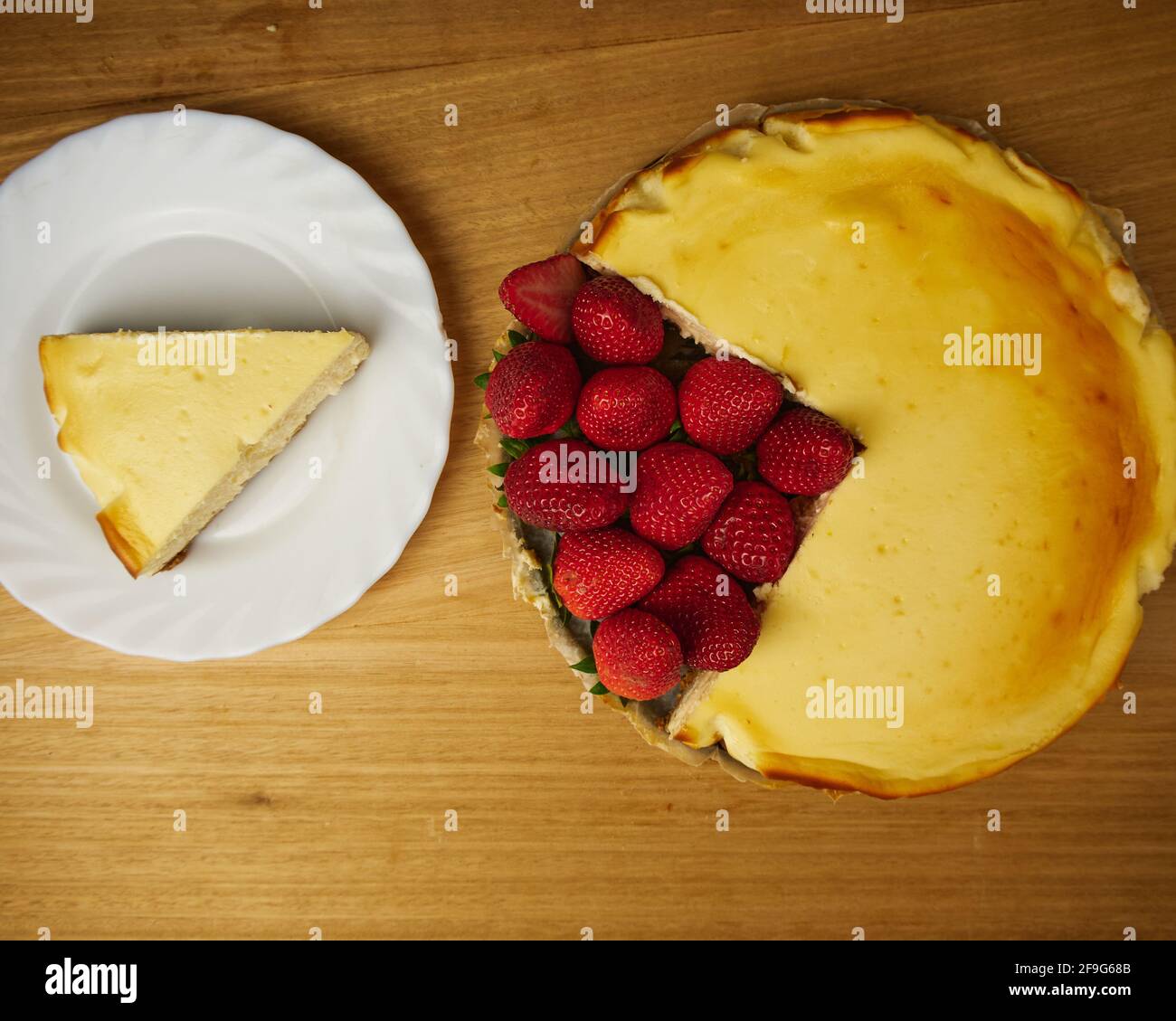 Cheescake con diverse fragole su sfondo di legno. Vista dall'alto Foto Stock