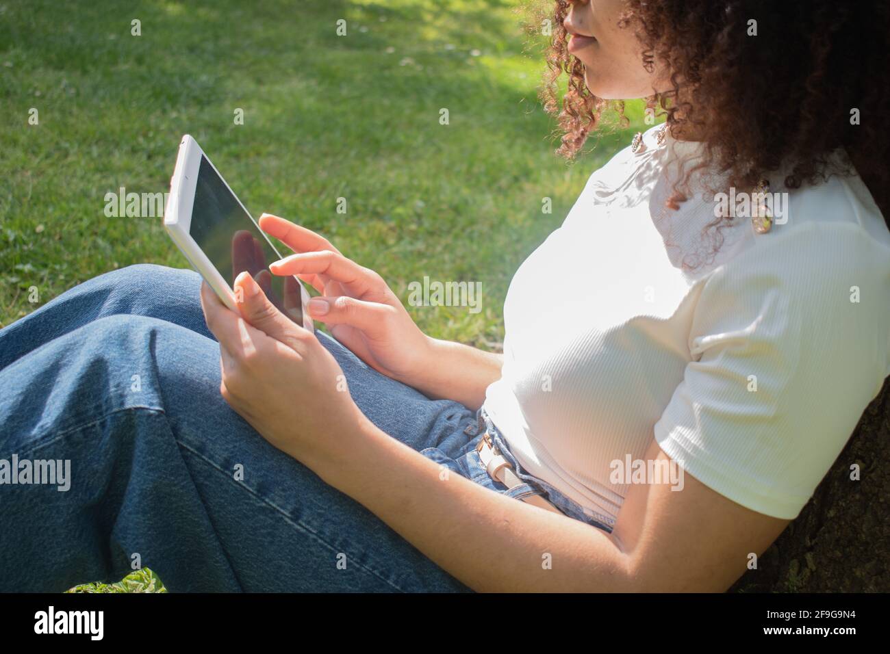 ragazza senza identità utilizzando un tablet in un parco Foto Stock