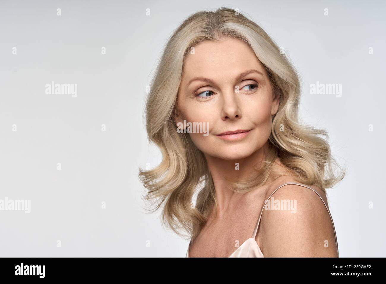 Ritratto della donna di mezza età che fa pubblicità alla cura del viso e del corpo su sfondo bianco. Foto Stock