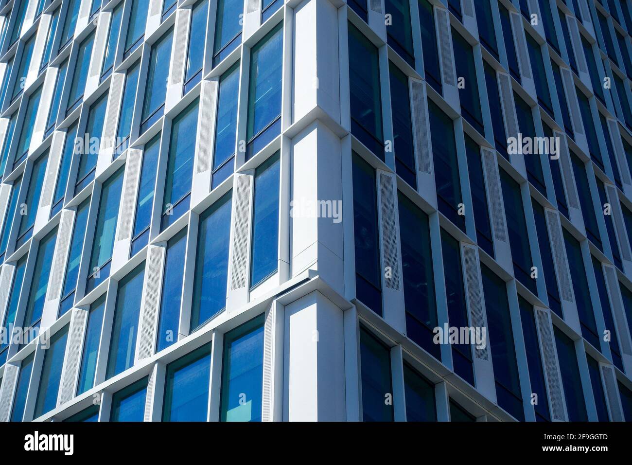 Al bordo dell'edificio per uffici con grandi finestre, con lato luminoso illuminato dal sole e lato scuro e ombreggiato Foto Stock