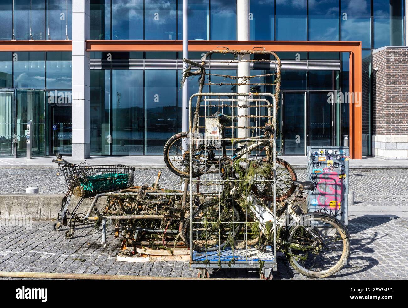 Pulizia del canale. Oggetti recuperati dalla pesca con calamite al Grand Canal Docks di Dublino, Irlanda, tra cui vecchie biciclette e un carrello per lo shopping. Foto Stock