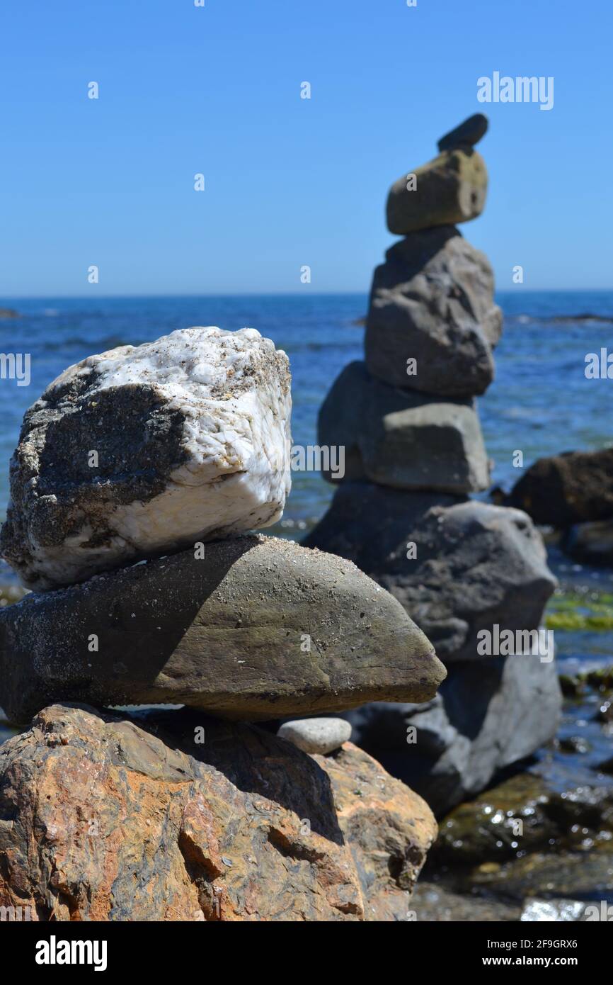 Pile di massi su una spiaggia a Fuengirola, Spagna - sculture di Art Rock di quattro o cinque grandi pietre, contro il cielo blu e il mare calmo. Foto Stock