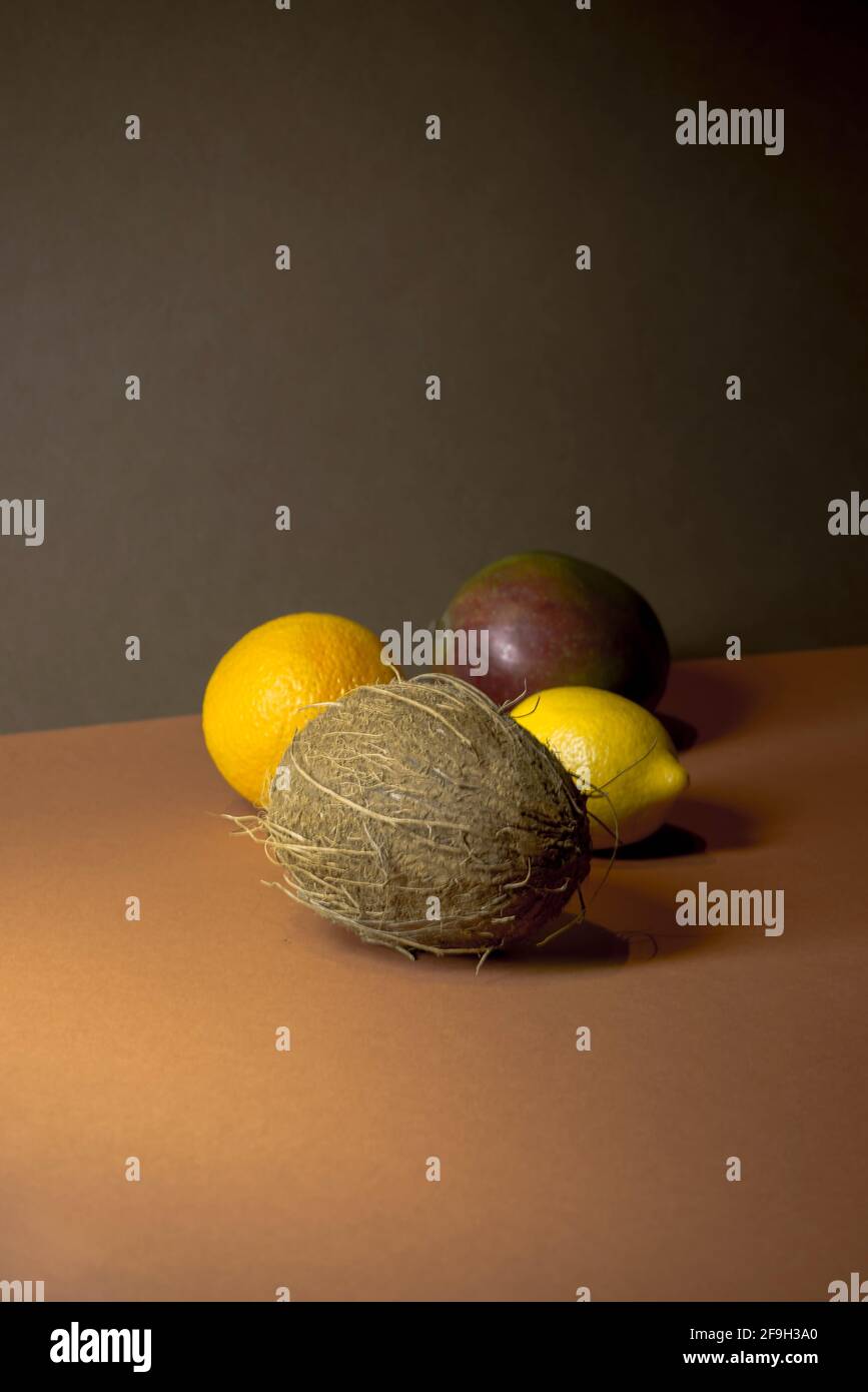 Limone, cocco, mango, arancio su uno sfondo a due colori. Concetto di frutta tropicale minimo. Colori alla moda marrone e arancione. Estate vibes idea. Foto Stock