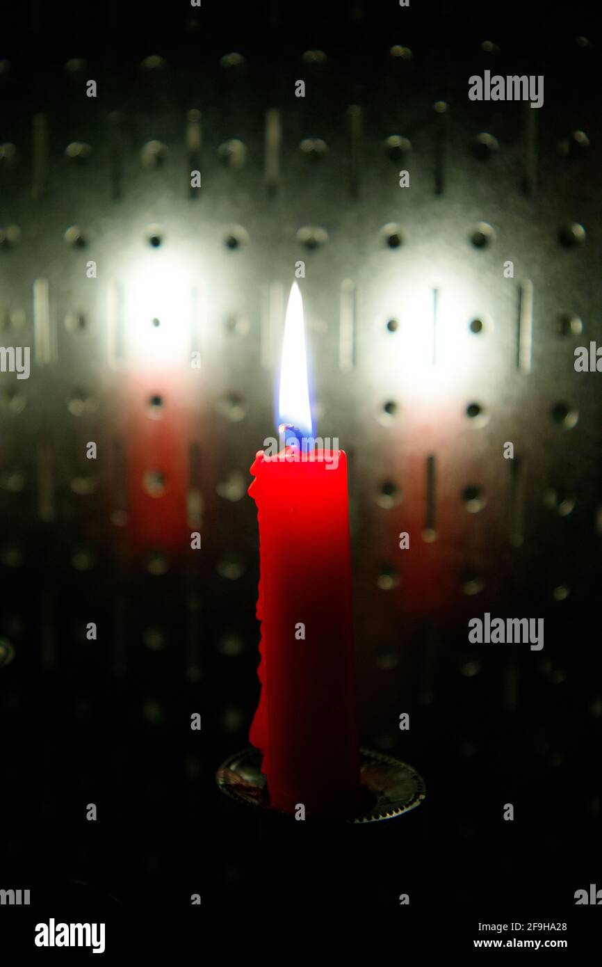 La candela rossa brucia contro lo sfondo di acciaio Foto Stock