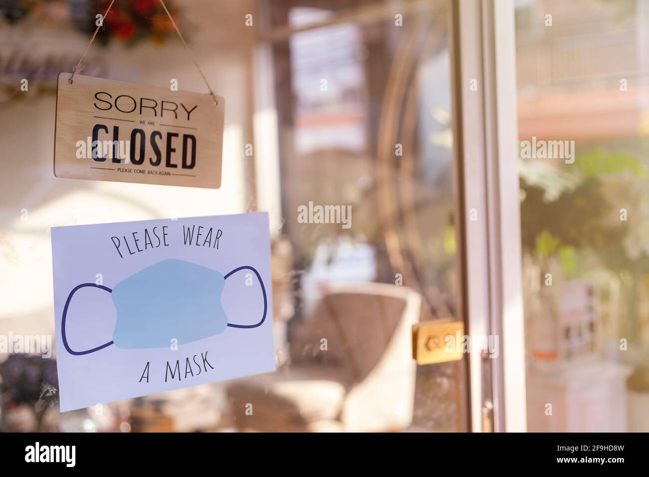 Siamo spiacenti siamo chiusi cartello legno e si prega di indossare la maschera per entrare in carta su porta di vetro protezione per pandemia di coronavirus. Chiudi negozio, ristorante Foto Stock
