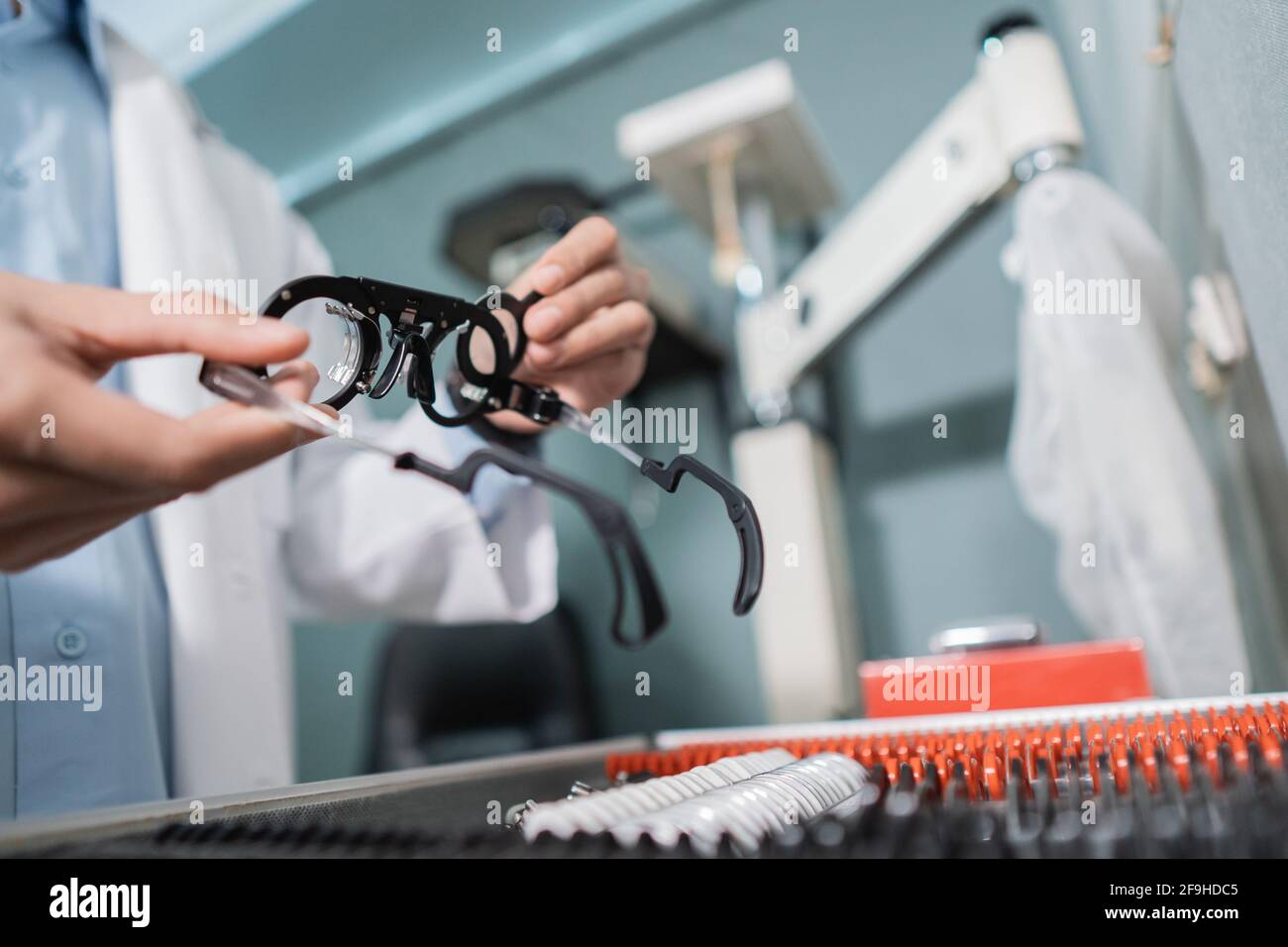 una mano del medico dell'occhio sta prendendo una lente di prova degli occhiali indicatore in una scatola contenente un set di lenti Foto Stock