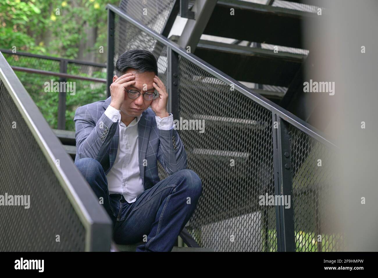 Uomo d'affari stressato seduto alle scale all'aperto. Crisi aziendale o concetto di stress lavorativo. Foto Stock