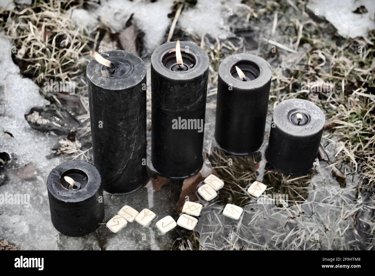 Gruppo di candele e rune nere che bruciano nell'acqua. Sfondo esoterico, gotico e occulto, Halloween mistico e wicca concetto all'aperto. Foto Stock