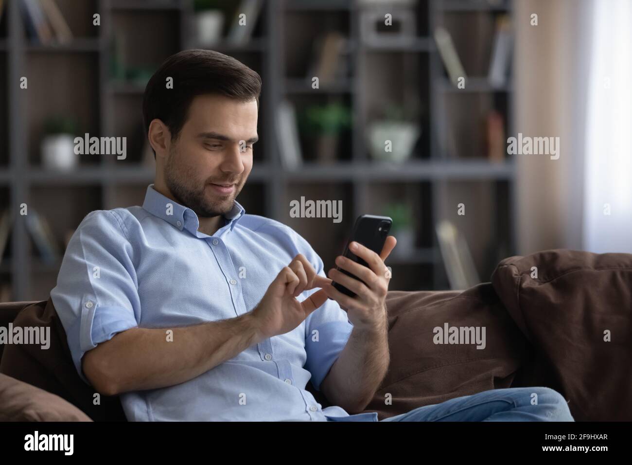 Uomo sorridente usa il gadget del cellulare testando online Foto Stock