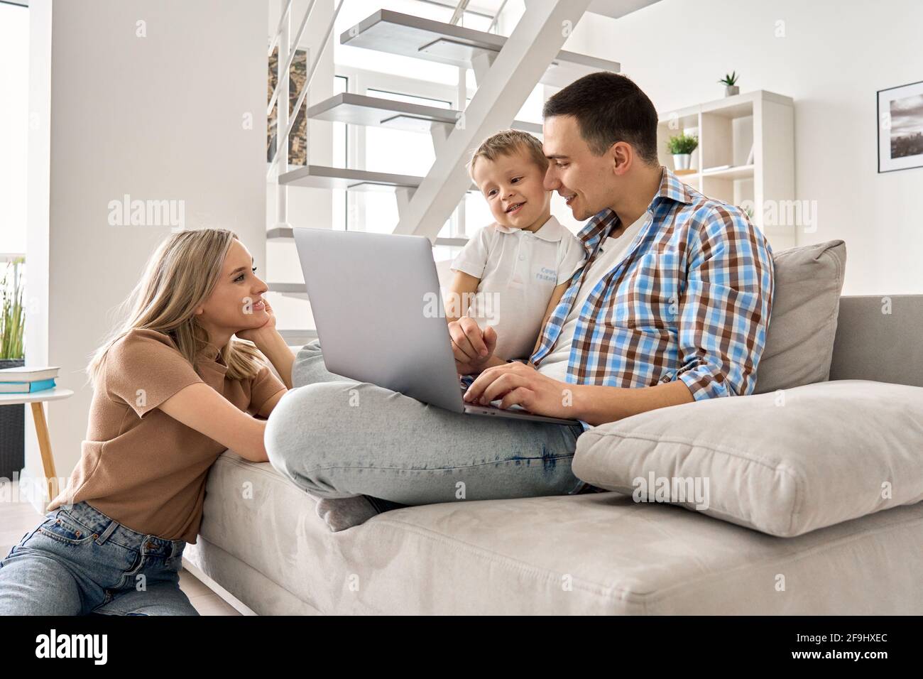 Felice famiglia madre, padre e figlio carino divertirsi utilizzando il computer portatile a casa. Foto Stock