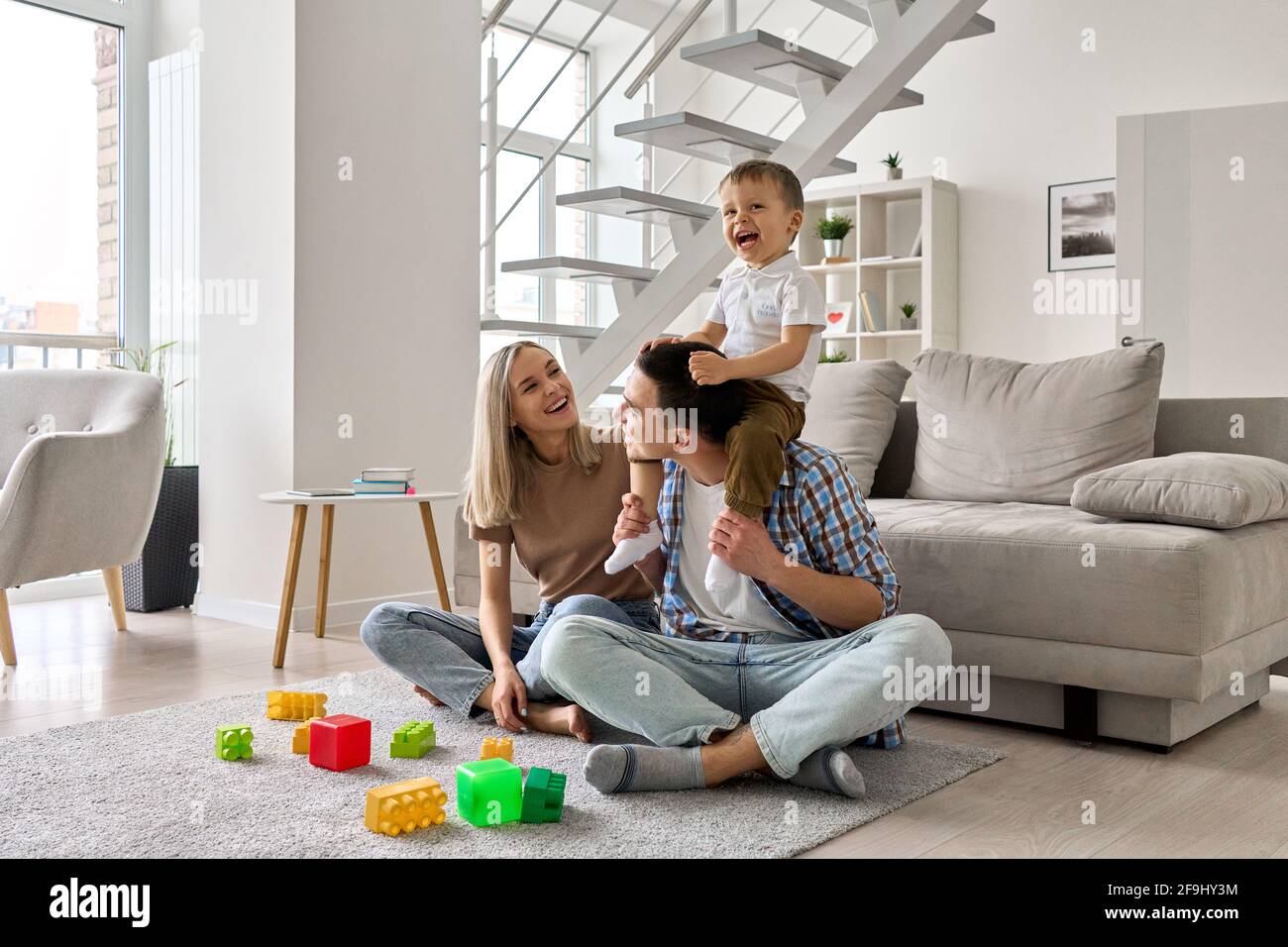 Felici i genitori e il figlio del bambino del toddler che godono di passare il tempo insieme a casa. Foto Stock