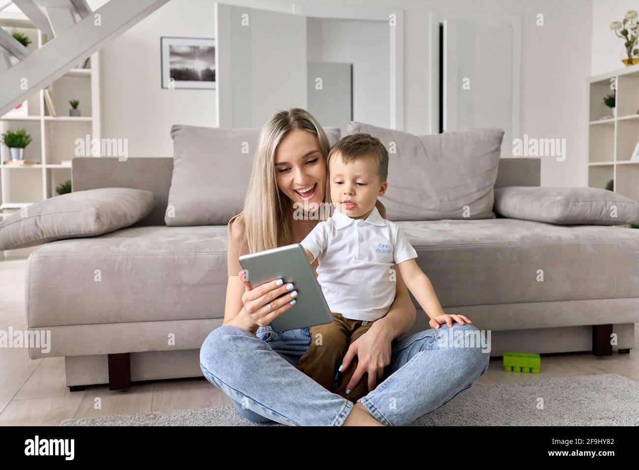 Felice mamma di famiglia che insegna il figlio carino utilizzando il tablet digitale a casa. Foto Stock