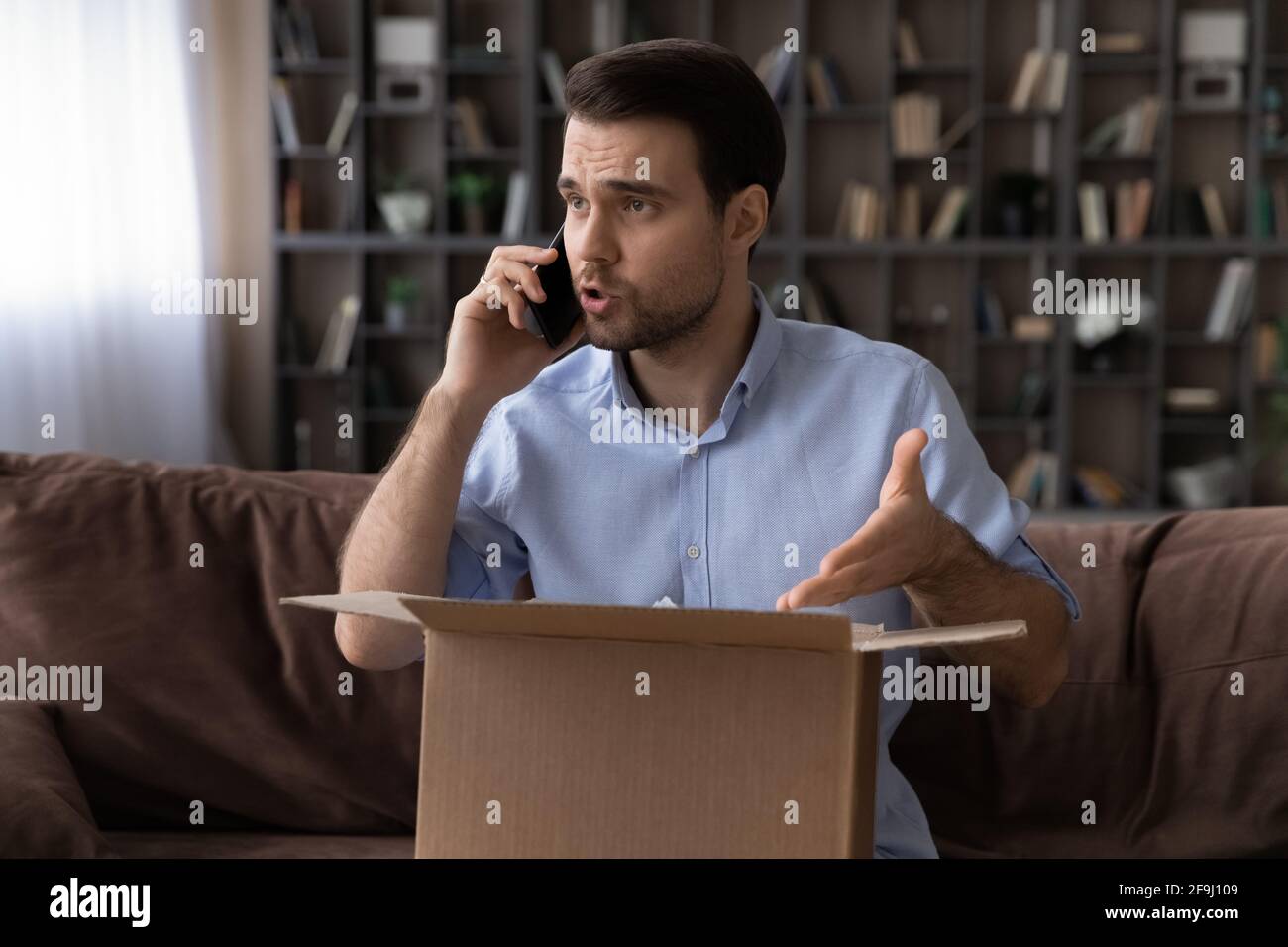 Uomo infelice parlare con la società di consegna di errori di spedizione Foto Stock