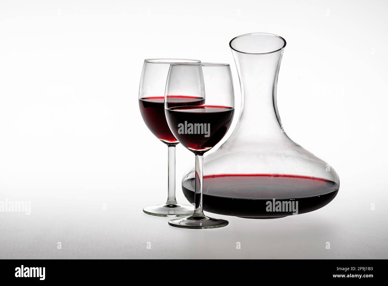 Decanter e due bicchieri di vino rosso su sfondo bianco Foto Stock