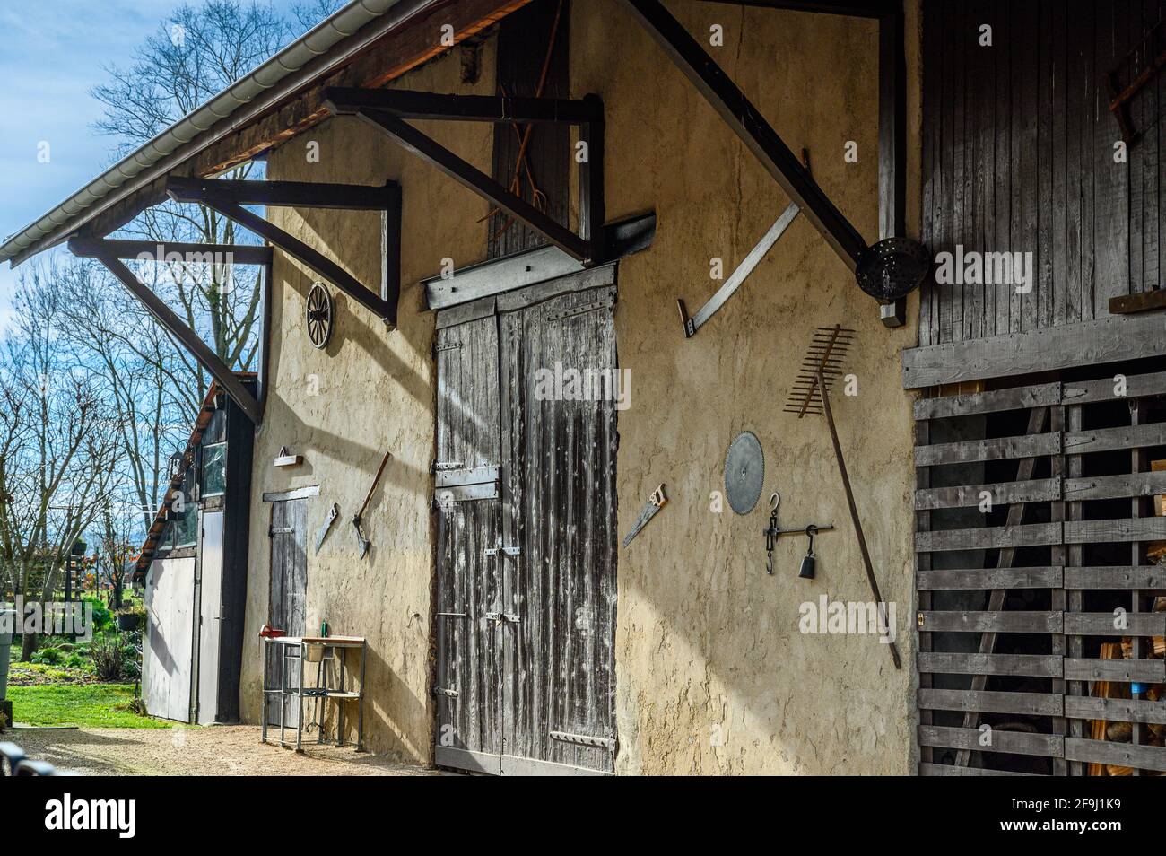 Vecchio usurato Rural Barn porta e gli strumenti di Hanging sul muro Foto Stock