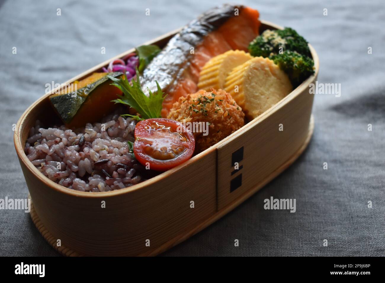 Wappa Bento, scatola per pranzo giapponese realizzata con piatto di legno rotondo, salmone alla griglia con sale Foto Stock