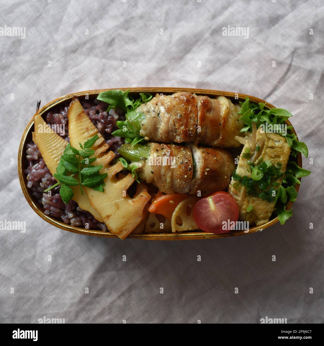 Wappa Bento, scatola per pranzo giapponese realizzata con piatto di legno rotondo, fagioli a bottoncino avvolti con carne Foto Stock