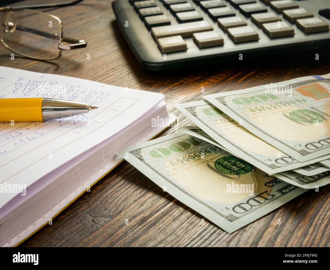Dollari e un calcolatore con i calcoli domestici di finanza. Foto Stock