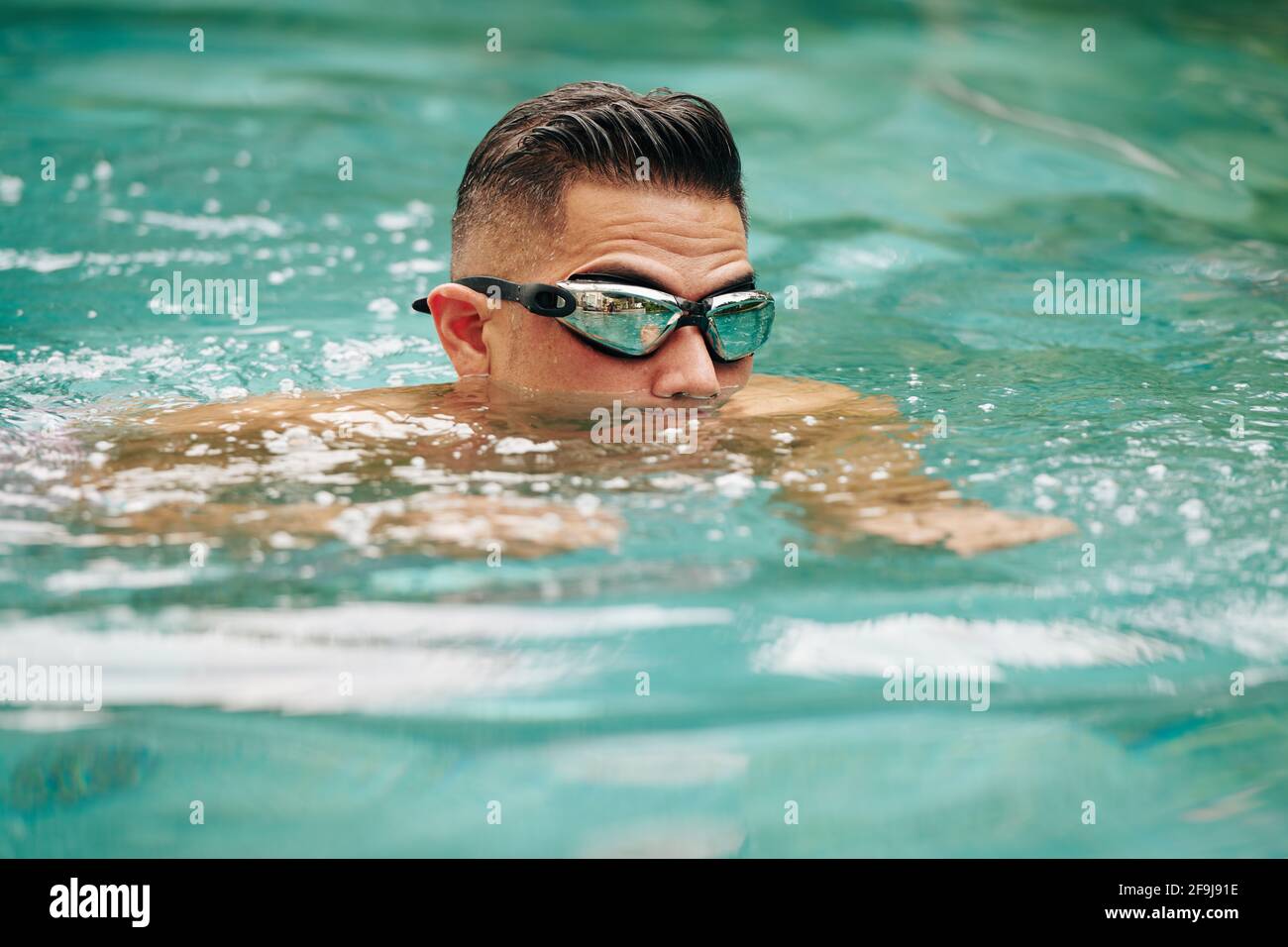 Uomo in occhialini a specchio che nuotano in piscina all'aperto Foto stock  - Alamy