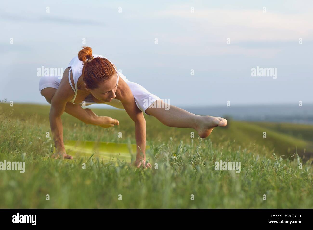 Amante dello yoga motivato che si bilancia sulle mani praticando asana in pace campo estivo Foto Stock