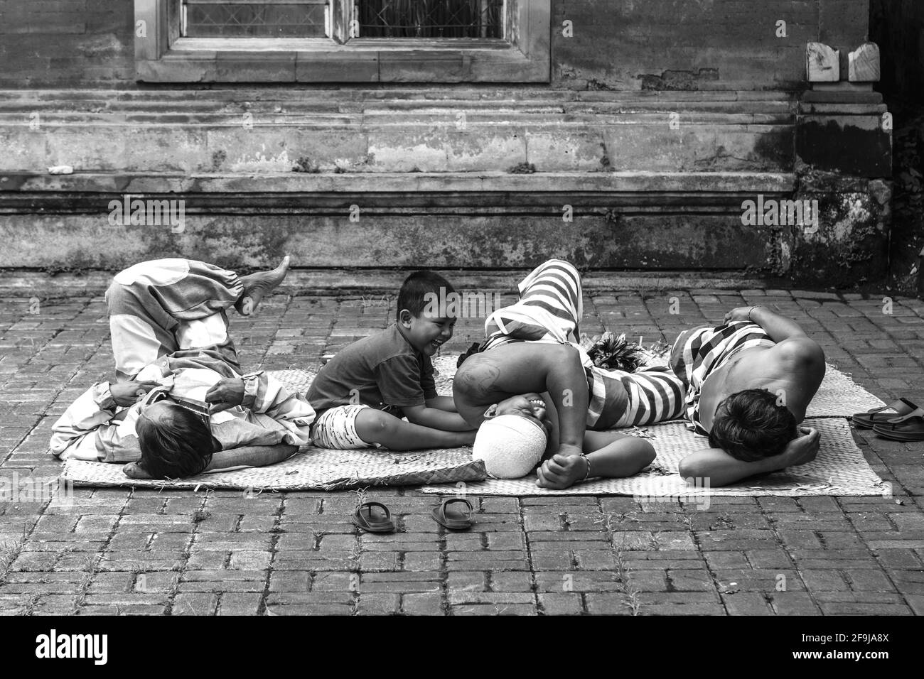 Un bambino gioca con alcuni degli artisti prima DI UNO spettacolo di danza tradizionale Balinese Barong e Kris, Batabulan, Bali, Indonesia. Foto Stock