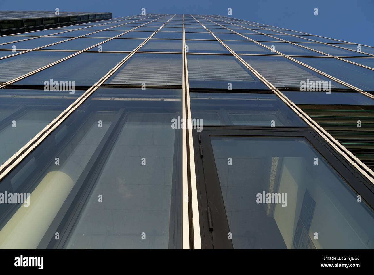 Foto ad angolo basso di un edificio con pareti di vetro sotto la luce del sole e un cielo blu Foto Stock