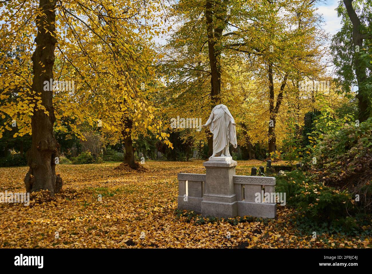 Grabmal mit beschädigter statue einer Frau, Frau ohne Kopf, Bäume im Herbstlaub, Luisenstädtischer Friedhof, Kreuzberg, Berlino, Germania Foto Stock