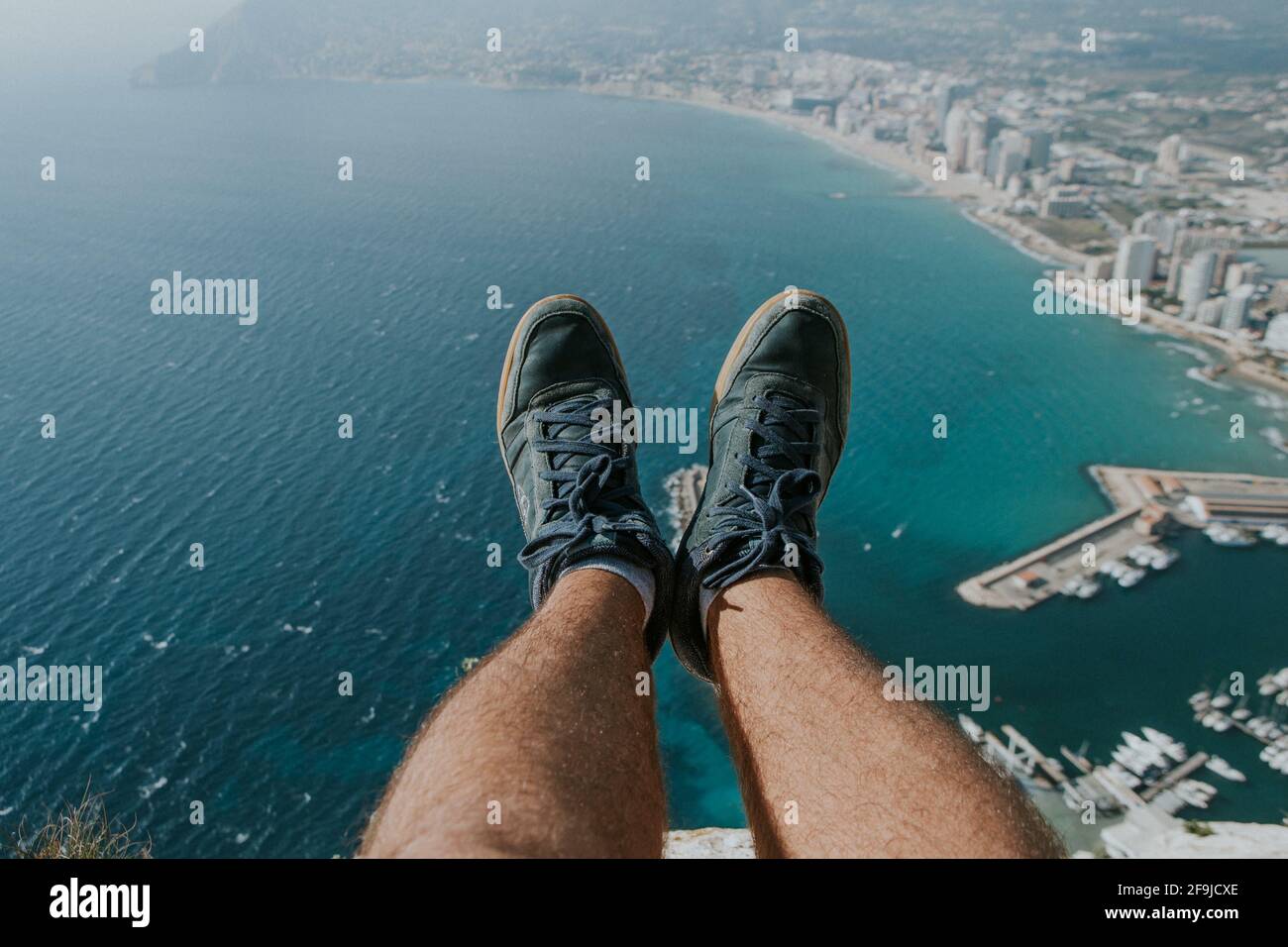 Piede dell'uomo su una scarpa che gode la vista di Città e zona costiera di Calpe in Spagna Foto Stock