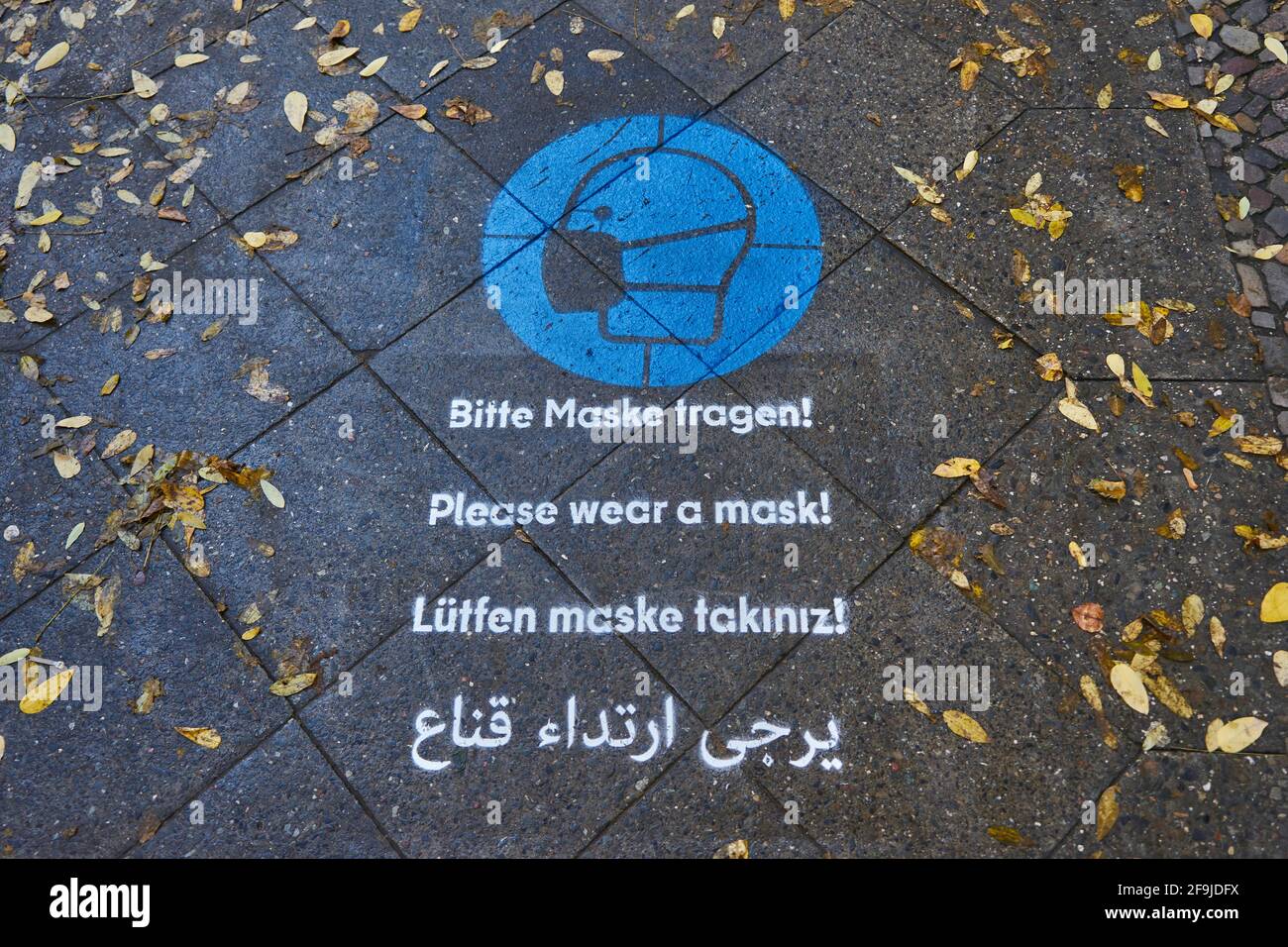 Boden-Piktogramm mit Hinweis zum Masken tragen, mehrsprachig, Infektionsschutz gegen Covid 19, Bergmannstraße, Kreuzberg, Berlin, Deutschland Foto Stock