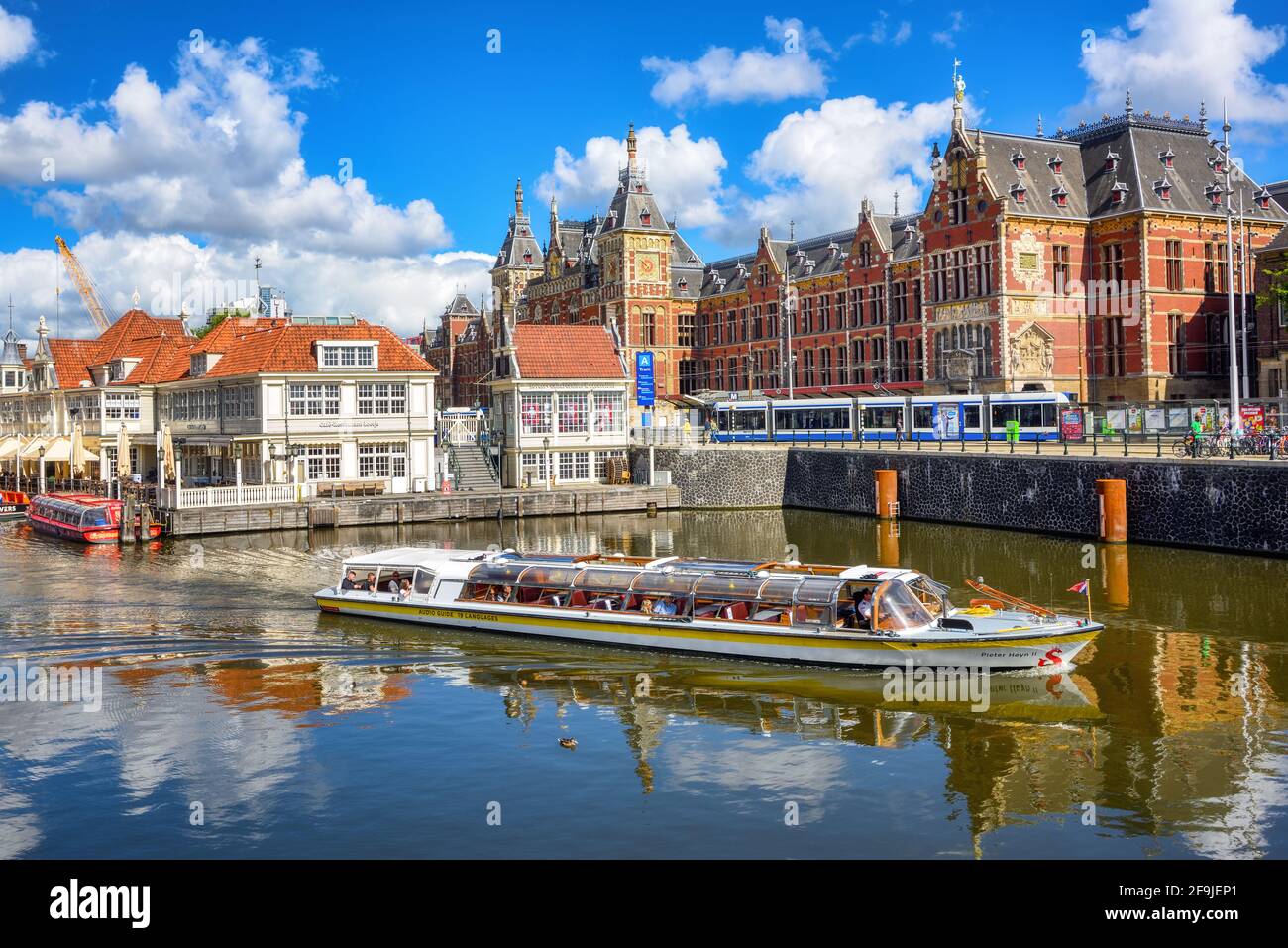 Amsterdam, Paesi Bassi - 12 luglio 2020: Battello turistico e tram di fronte alla stazione centrale di Amsterdam, il principale centro turistico di Amsterdam Foto Stock