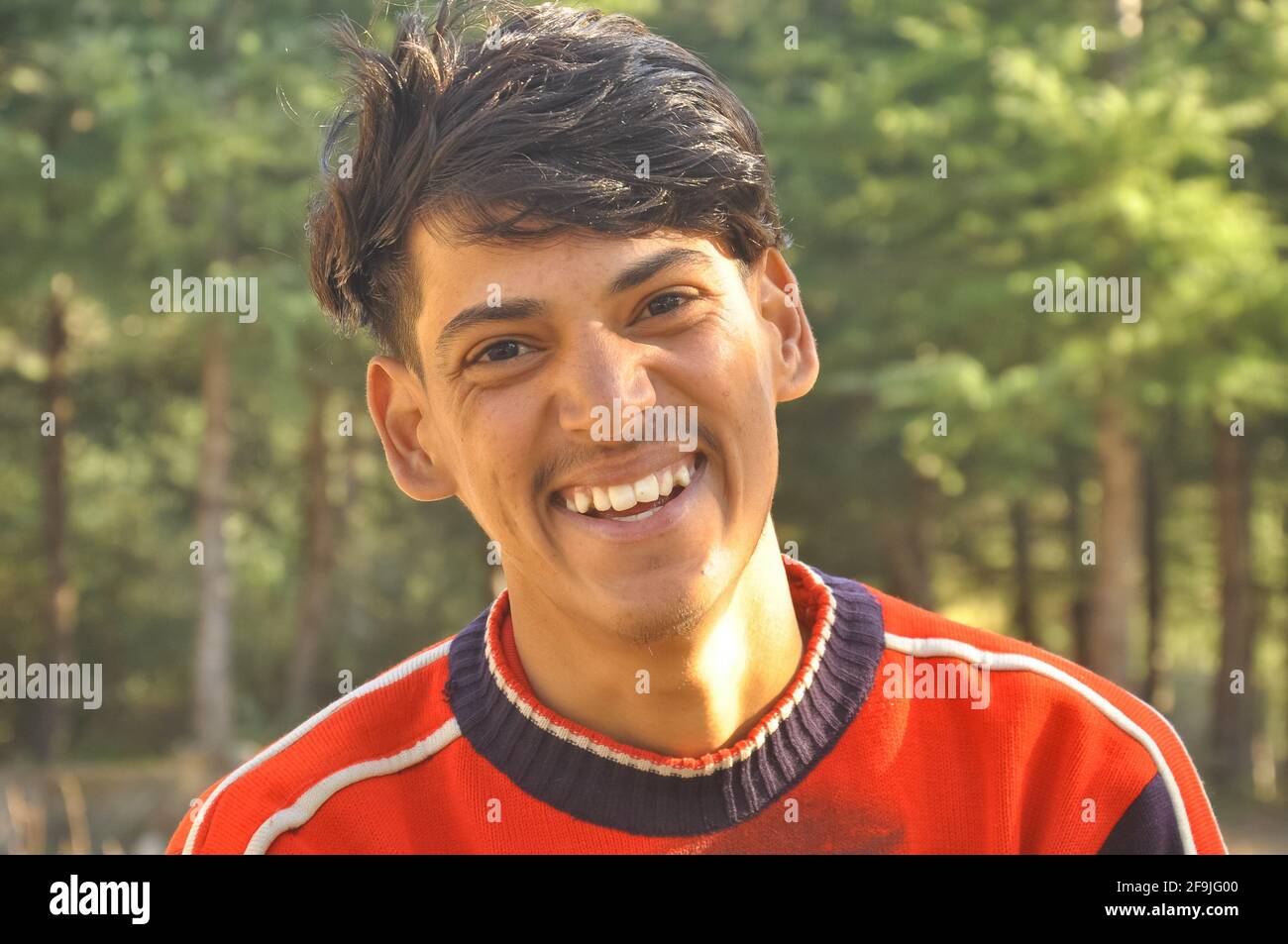 Primo piano di un giovane ragazzo indiano sorridente all'aperto con una fotocamera, Laughing giovane ragazzo - Stock Photo Foto Stock