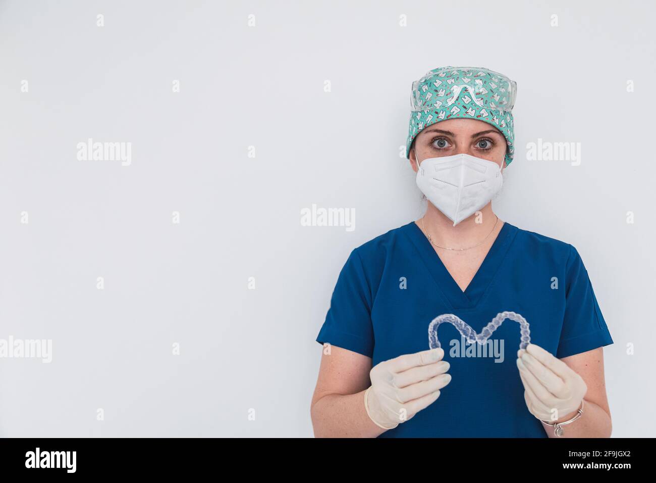 Medico femminile che tiene due allineatori dentali trasparenti a forma di cuore. Foto Stock