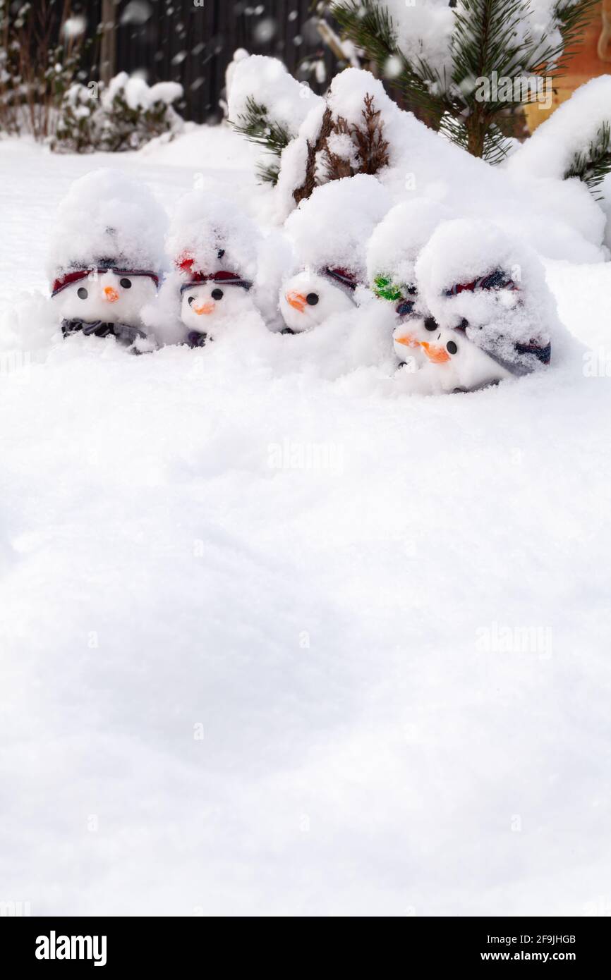 Simpatici pupazzi di neve coperti da una fresca nevicata con cappelli, sciarpe e carote nasi. Inverno neve divertimento e paesaggio homour con spazio bianco Foto Stock