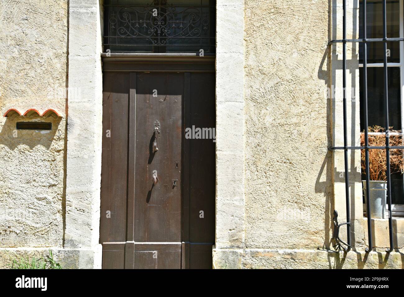 Tipica facciata rurale in stile Provençal con una porta di legno marrone nel pittoresco villaggio di Lourmarin a Vaucluse, Provenza Francia. Foto Stock