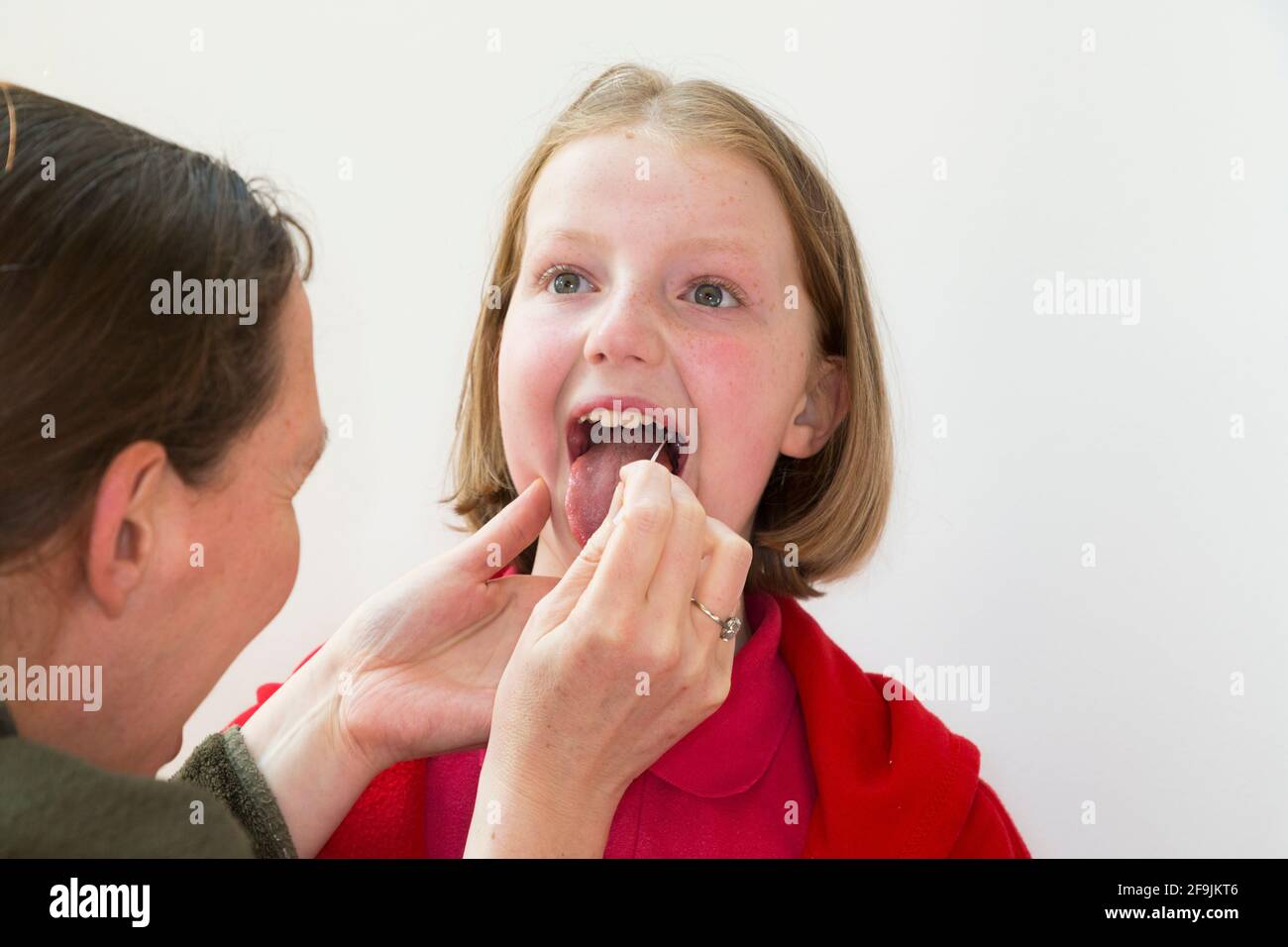 Età scolastica bambino scuola primaria ragazza di 11 anni / anni con campioni prelevati dalla gola per l'uso in un test di flusso laterale LFT dalla società cinese Innova. Inghilterra Regno Unito. (123) Foto Stock